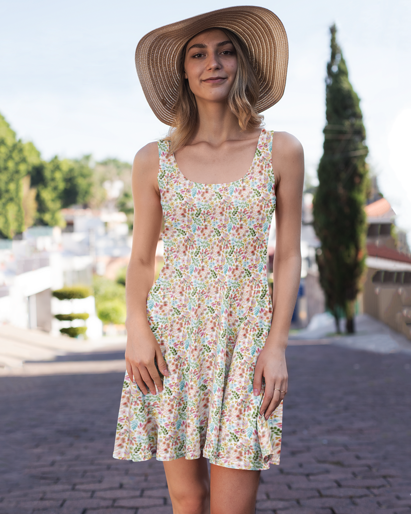 Garden Gala pastel floral sleeveless scoop neck fit and flare dress on smiling thin woman in a hat standing in front of a street scene